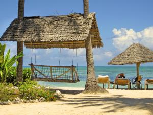 una playa con sillas y sombrilla y el océano en Blue Oyster Hotel, en Jambiani