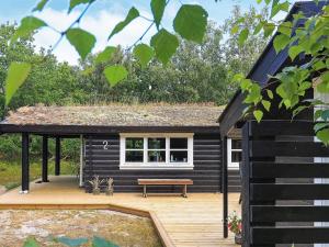 a small black cabin with a bench on a deck at Seaside Escape in Laeso - By Traum Ferienwohnungen in Læsø
