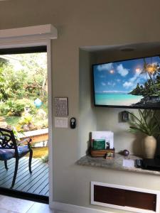 uma sala de estar com uma televisão de ecrã plano na parede em The Secret Garden Room em Kapaa