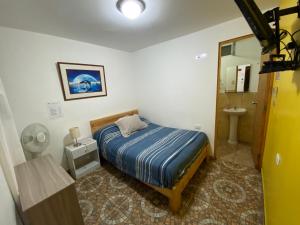 a small bedroom with a bed and a bathroom at Atenas Backpacker Hospedaje in Paracas