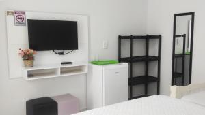 a bedroom with a tv on a white wall at Mar dos Sonhos Suítes in Ubatuba