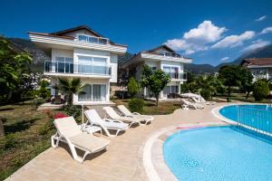 a villa with a swimming pool and lounge chairs at Villa Anemon in Fethiye
