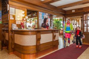 a man and a woman and child on skis standing at a bar at Hotel Europa in San Martino di Castrozza