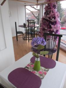 una mesa con un jarrón con flores púrpuras. en Ayenda Eloina, en Bogotá