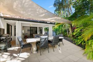 a patio with a table and chairs and a grill at Central Tropical Oasis with Pool in Noosaville