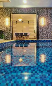 uma piscina com piso de azulejo azul e cadeiras em Spring Fields Homestay by Sizma em Semenyih