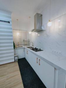 a white kitchen with a sink and a stove at Spring Fields Homestay by Sizma in Semenyih