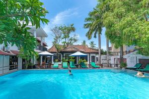 a pool at a hotel with people in the water at Nostalgia Hotel and Spa in Hoi An