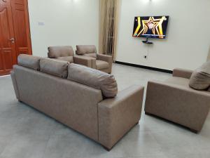uma sala de estar com um sofá e duas cadeiras em FAD Home & Apartments em Dodoma