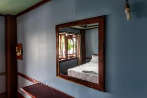 a mirror on a wall with a bed in a room at Nongsak Riverside Guesthouse & Nongsak Guesthouse in Ban Khon