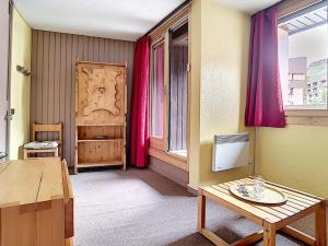 um quarto com uma mesa e uma janela com cortinas vermelhas em Studio Les Menuires, 1 pièce, 2 personnes - FR-1-344-1130 em Les Menuires