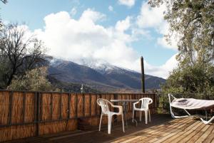 een terras met twee stoelen en een tafel met bergen op de achtergrond bij Ladera Encanto in Caleu