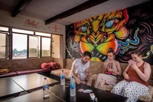 three people sitting on a couch in a living room at Friends Guest House & Hostel- near TAJ MAHAL in Agra