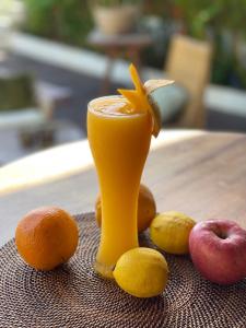 a glass of orange juice on a table with fruit at Ahana Resort El Nido in El Nido
