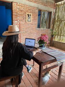 a woman sitting at a picnic table with a laptop at LÍZU Tu casa en un pueblo zapoteca in Teotitlán del Valle