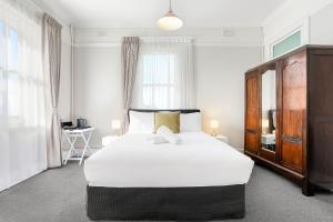 Un dormitorio con una gran cama blanca y una ventana en Grand View Hotel, en Wentworth Falls
