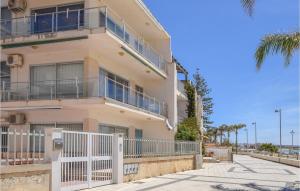 ein Apartmenthaus mit einem weißen Zaun und Palmen in der Unterkunft Amazing Apartment In Marina Di Ragusa in Marina di Ragusa