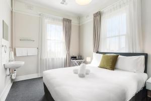 una camera da letto con un grande letto bianco con un orsacchiotto sopra di Grand View Hotel a Wentworth Falls