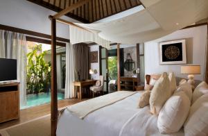 een slaapkamer met een groot bed en een televisie bij Goya Boutique Resort in Ubud