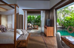 a bedroom with a bed and a tv and a pool at Goya Boutique Resort in Ubud