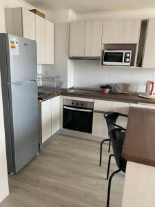eine Küche mit einem Kühlschrank aus Edelstahl und einer Mikrowelle in der Unterkunft pacifico 3100 in La Serena