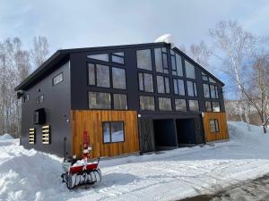 a house in the snow with a sled in front of it at Annupuri Onsen Chalet in Niseko