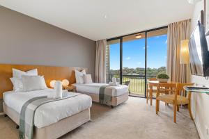 a hotel room with two beds and a balcony at Fairway Views – Moonah Apartment 23 in Fingal