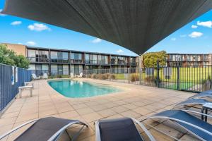 a patio with chairs and a swimming pool at Fairway Views – Moonah Apartment 23 in Fingal