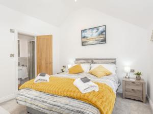 a white bedroom with a large bed with yellow pillows at Pogles Wood Cottage in Skipton