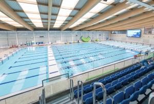 a large swimming pool with blue chairs in a building at Sparkling Space - Twin or King Beds in Bangor