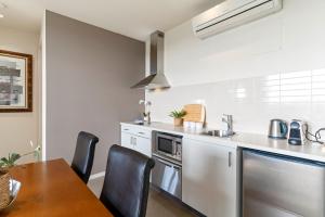 a kitchen with a table and a sink and a stove at Fairway Views – Moonah Apartment 24 in Fingal