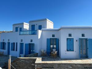 a row of white buildings with blue doors and tables at Cavo Lacia in Gavrio