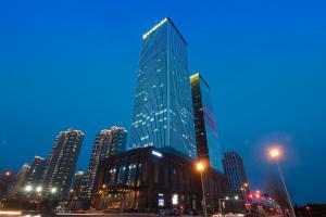 een hoog glazen gebouw in een stad 's nachts bij Qingdao Jinshi International Hotel in Qingdao