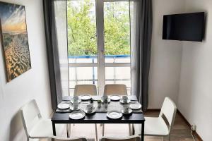 einen Esstisch mit weißen Stühlen und ein Fenster in der Unterkunft Apartments Halle West in Nietleben