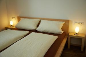 two beds in a room with two lamps on tables at Business Homes - Das Apartment Hotel in Lauchheim