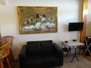 a living room with a couch and a painting on the wall at Fare Arearea Sweet Studio in Papeete