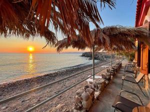 a beach with chairs and umbrellas and the ocean at Terracotta Boutique Beach Studios in Mythimna