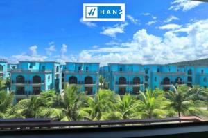 a view of a blue building with palm trees at HANZ Sang Sang Hotel in Phu Quoc