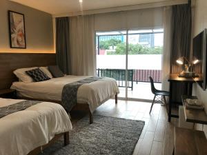 a hotel room with two beds and a balcony at Celosia Chiang Mai Hotel in Chiang Mai