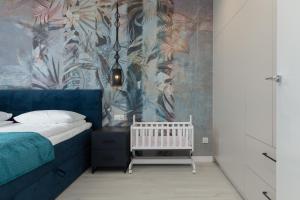 een slaapkamer met een wieg en een blauwe muur bij Mielno Sea & Lake Apartment by Renters in Mielno