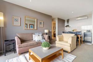 een woonkamer met een bank, stoelen en een tafel bij Fairway Views – Moonah Apartment 23 & 24 in Fingal