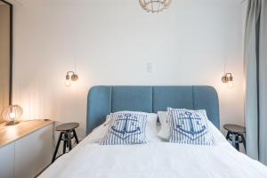 - une chambre avec un lit blanc et 2 oreillers bleus dans l'établissement Apartment N14 direkt am Nordseedeich mit Blick auf den See, à Nordstrand