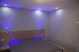 a bedroom with a bed with purple lights on it at LVC,LAC & NYC Apartshotel Faleza in Galaţi