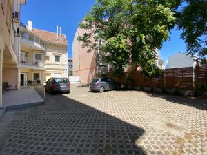 Deux voitures garées dans un parking à côté d'une clôture dans l'établissement Tisza Alfa Hotel, à Szeged