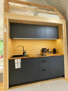 una cocina en una casa pequeña con un loft en Borowy Glamp więcej niż domki, en Męcikał