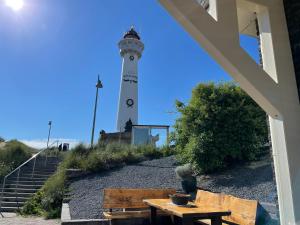 a lighthouse on the beach with a table and benches at Droomvakanties Egmond Appartement van Speijk in Egmond aan Zee