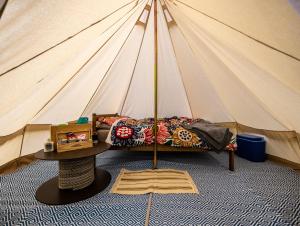 a bed in a tent with a table in front at Naturally Glamping in Kingsteignton +20 photos