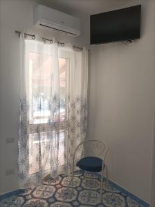 una silla sentada frente a una ventana en b&b Luisa, en Marina di Camerota