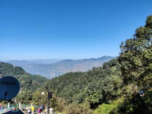 un grupo de personas de pie en una colina con montañas en el fondo en Breeze 2BHK By Wabi Sabi Stays Mall Road 5 Mins Walk, en Mussoorie