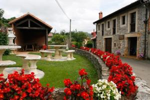 um jardim com flores vermelhas e brancas e um edifício em Rodiles Rural Apartamentos em Selorio